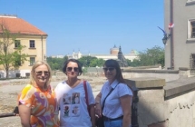 Trzy uśmiechnięte kobiety na tle zabytkowych budynków 