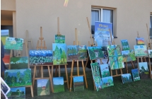 Wystawa obrazów na sztalugach na tle ściany 