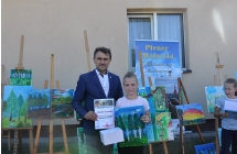 Usmiechnieta dziewczynka i mężczyzna. Dziewczynka trzyma przed sobą dyplom 