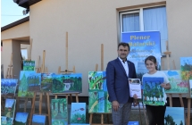 Uśmiechnięta dziewczynka z dyplomem i obrazem, obok niej elegancki mężczyzna. 