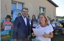 Uśmiechnięta kobieta i męzczyzna, w tle inni ludzie oraz wystawy obrazów 