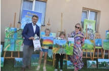 Mężczyzna, kobieta oraz dwójka dziewczynek trzymających obraz i dyplomy 