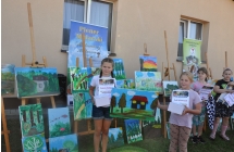 Cztery dziewczynki z obrazami i dyplomami na tle obrazów 