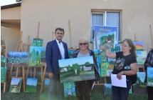 Dwie radosne kobiety, obydwie trzymają obrazy w rękach. Pozuje z nimi przedstawiciel samorządu 