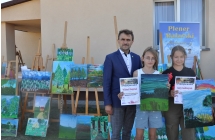 Mężczyzna wraz z dwiema dziewczynkami, które trzymają dyplomy oraz dyplomy 