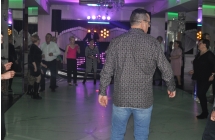 Kilkanaście osób bawiących się do muzyki, stoją w kole, na scenie DJ 