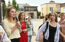 Kilkanaście osób i kobieta mówiąca do mikrofonu 